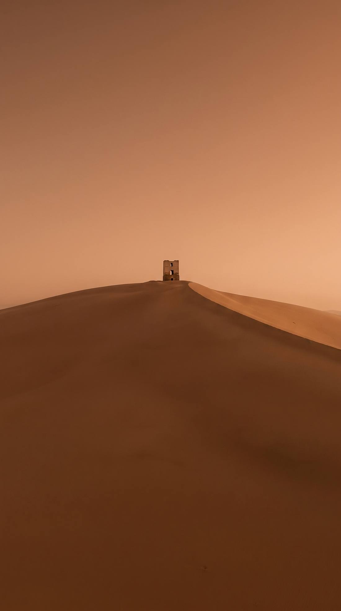 A vast dune ridge under a dust-coloured sky, a tiny doorway at the crest.